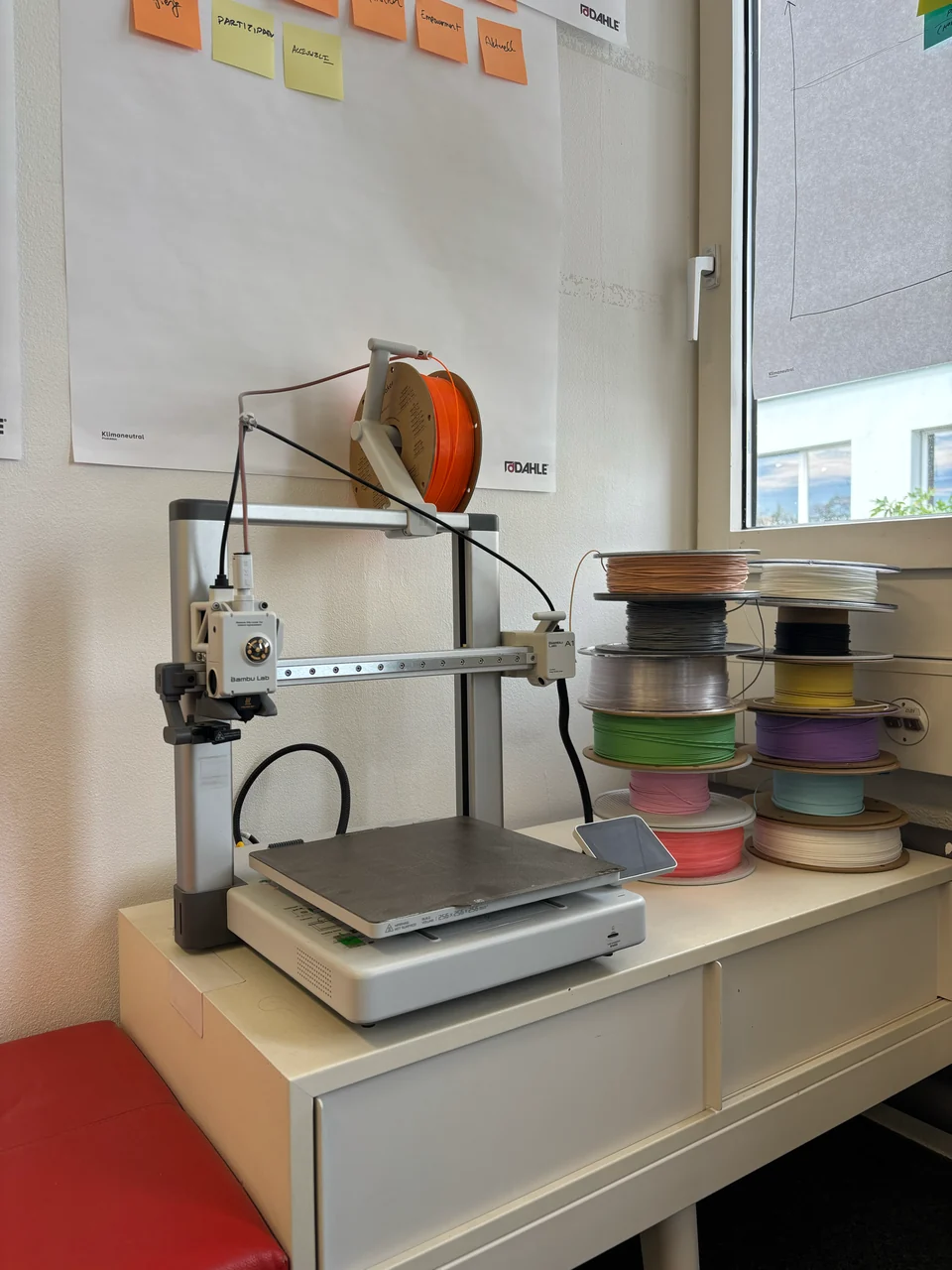 A 3D printer beside stacked rolls of filament