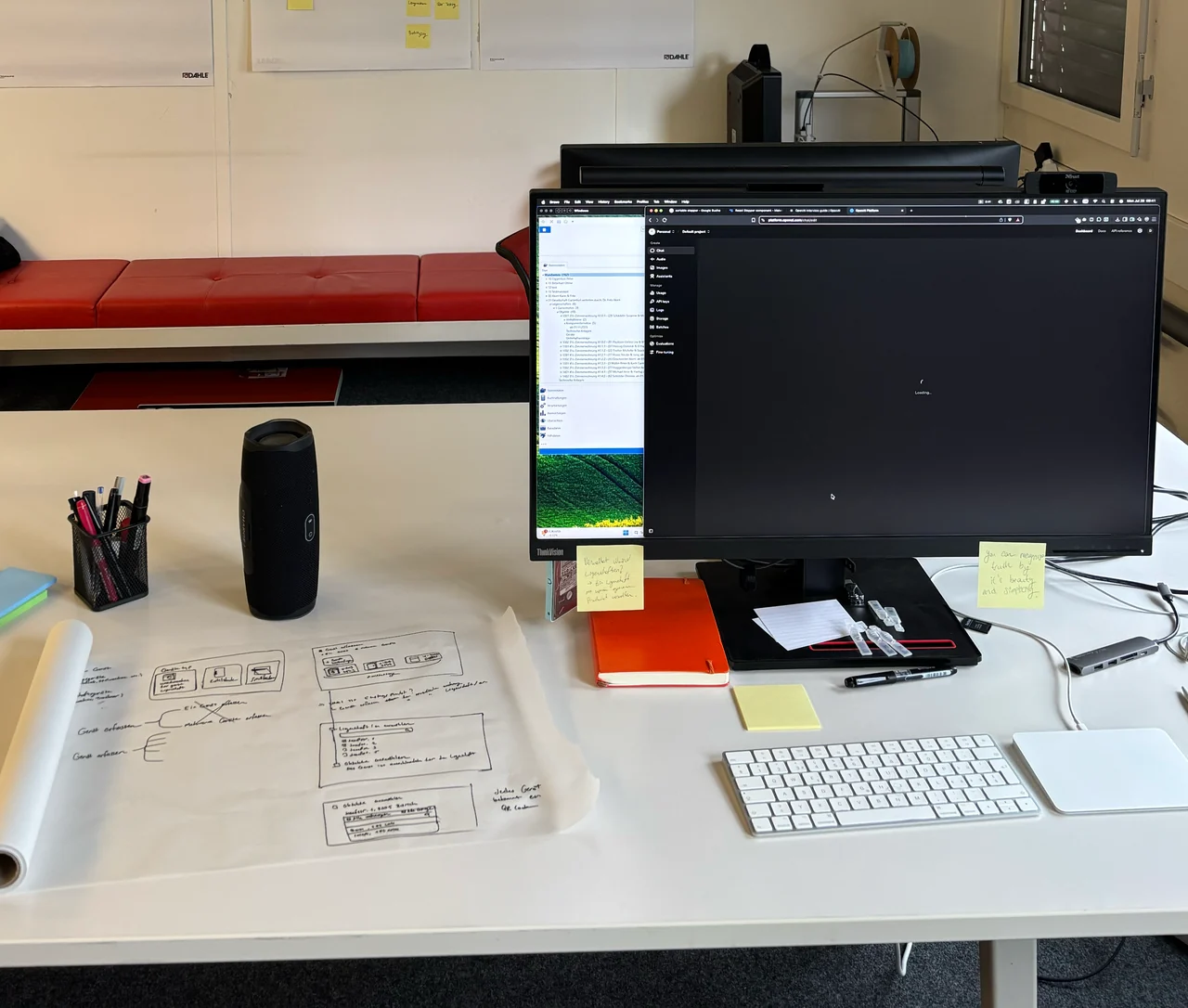 A desk with interface sketches, a keyboard and a monitor