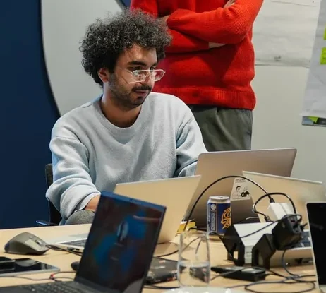 A colleague in conversation at a table with laptops