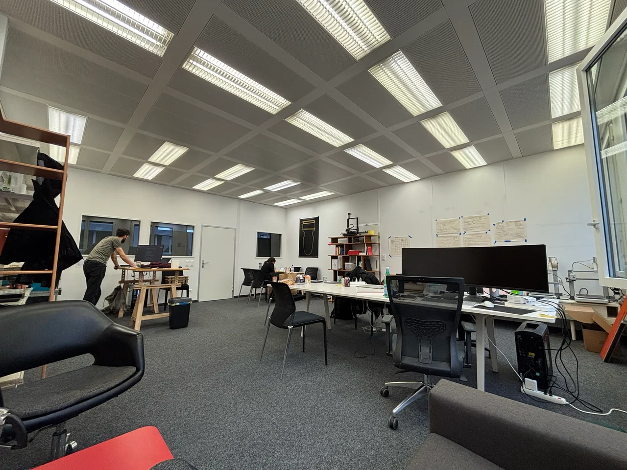 A wide view of the studio with desks, chairs and large windows